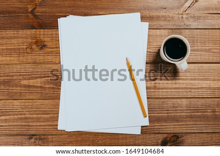 A4 blank paper, cup of coffee on wooden table background. Blank branding template.Photo blank form. Mock up for portfolio design.
