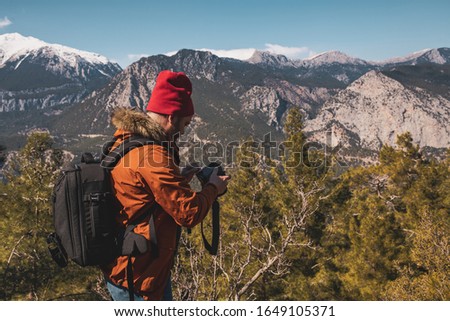 Young Caucasian male photographer on top of a mountain on clear day.