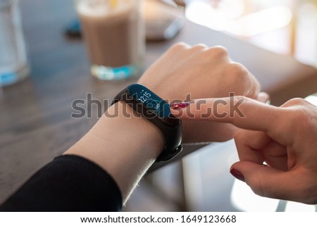 Woman use apps on smart bracelet. Tocuh display with right hand Royalty-Free Stock Photo #1649123668