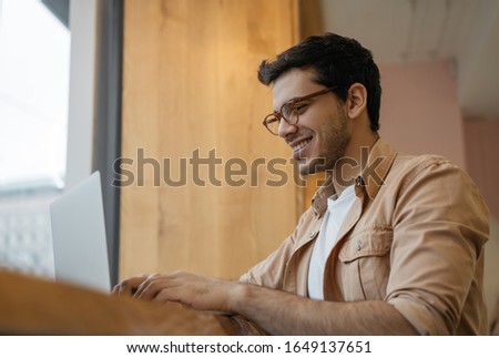 Professional copywriter working freelance project, typing on keyboard. Happy Indian business man using laptop computer, planning start up, sitting in modern office. Asian guy ordering food online 