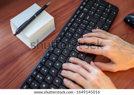 Close up. Picture of office table with papers, wireless keyboard and mouse. Woman typing on keyboard. Concept of work.