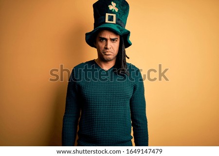 Young african american man wearing green hat with clover celebrating saint patricks day depressed and worry for distress, crying angry and afraid. Sad expression.