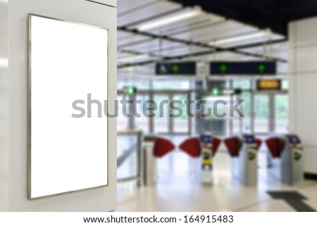 One big vertical / portrait orientation blank billboard on modern white wall with entrance of railway station background