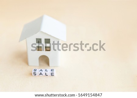Miniature toy model house with inscription SALE letters word on wooden backdrop. Eco Village abstract environmental background. Real estate mortgage property insurance sweet home ecology rent concept
