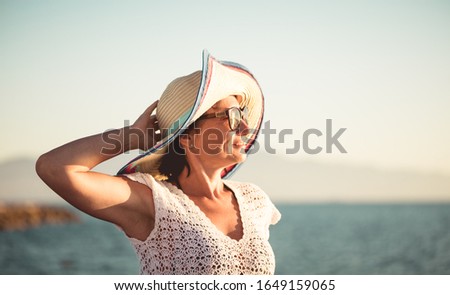 Profile of a happy woman in a beach hat who looks into the distance against the sea Royalty-Free Stock Photo #1649159065