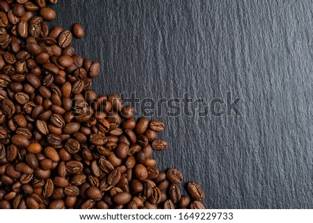 A lot of coffee beans laid out on slate with place for copy space. Close up.