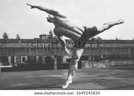 Contemporary art dance. Young handsome boy dancer with bare torso on industrial building. Black and white. Street urban lifestyle.