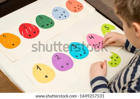 Different color paper eggs with numbers on one part and 
the equivalent amount of dots on other. Easter theme game, find other side of figure. 