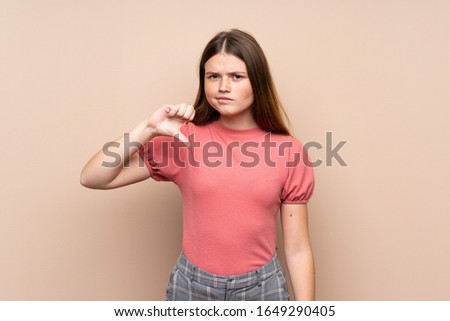 Ukrainian teenager girl over isolated background showing thumb down sign