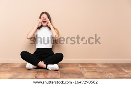 Ukrainian teenager girl sitting on the floor shouting and announcing something