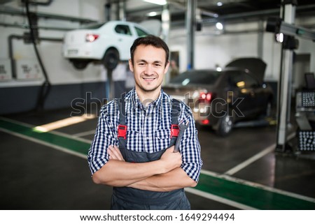Portrait of a young beautiful car mechanic in a car workshop, in the background of service.