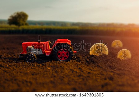 Earning money from agriculture concept, tractor on a field, plowing golden coins with dollar sign