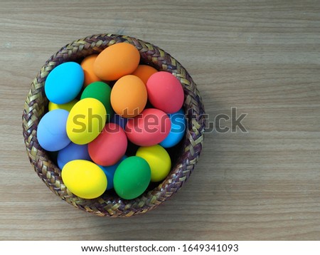 Colorful eggs in the basket on wooden background, Easter festival.