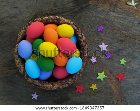 Top view colorful eggs in the basket on wooden background with paper star, Easter festival.