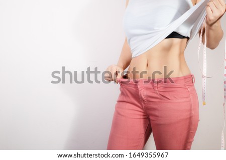 Young slim woman in fit pink pants. Fit woman wearing too fit pants. Healthcare and woman diet lifestyle concept to reduce belly and shape up healthy stomach muscle. Royalty-Free Stock Photo #1649355967