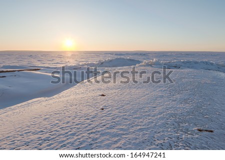 Sunset on horizon of the frozen winter lake. A natural winter background