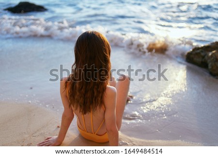 young woman in a beautiful swimsuit on white sand