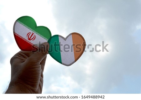 Hand holds a heart Shape Iran and Ireland flag, love between two countries