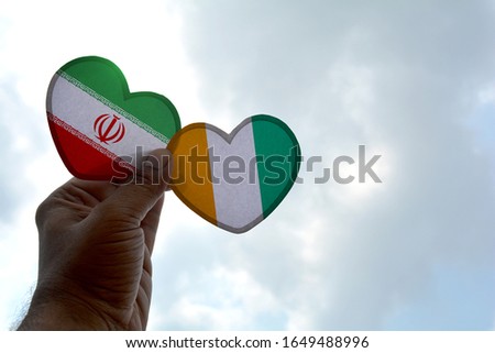 Hand holds a heart Shape Iran and Cote d'Ivoire flag, love between two countries