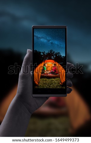 Night shooting on a smartphone. Couple in a tent under the starry night sky.