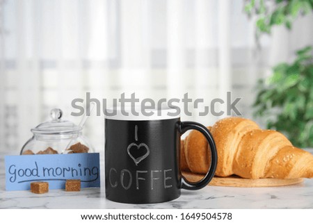 Delicious coffee, brown sugar, croissant and card with words GOOD MORNING on white marble table indoors