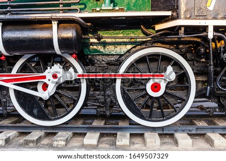 Old train wheels on rails in black, red and white.