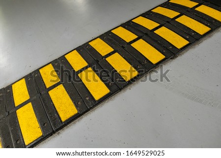 Striped black and yellow speed bump on a road.