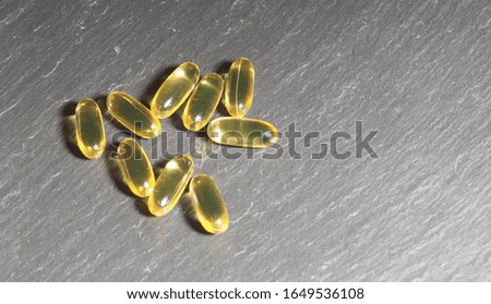 Many capsules Omega 3 on a gray stone background. Health care concept