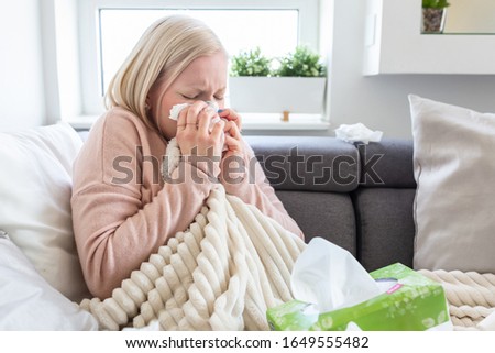 Sickness, seasonal virus problem concept. Woman being sick having flu lying on sofa looking at temperature on thermometer. Sick woman lying in bed with high fever. Cold flu and migraine.