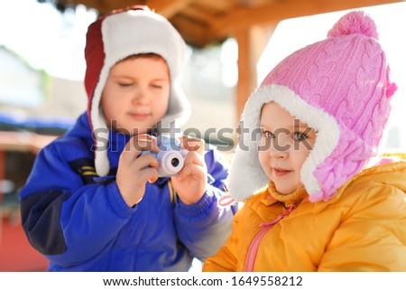 Little boy taking picture of girl outdoors. Future photographer