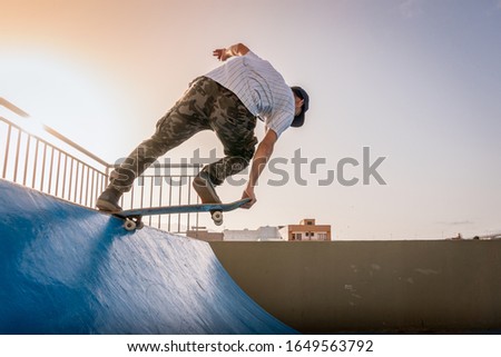 young skateboarder does a trick called "Tail nose Grab" on the ramp of a skate park at sunset