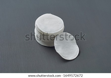 Heap of round cotton pads for hygiene lies on dark concrete table. Close-up