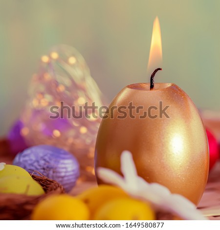 Greeting card Easter burning golden candle and chocolate eggs in colored foil. Festive Easter concept. Beautiful blurred background and glowing bokeh. Shallow depth of field. Toned image. Copy space. 