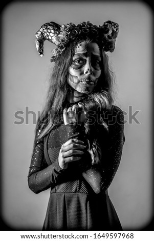 Halloween, black and white portrait of a young woman dressed as a Mexican skull with flowers on her head