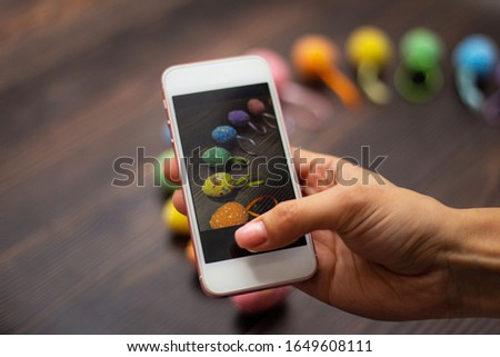 Woman makes a photograph of the colorful easter eggs with her cell phone. Mobile photo. Copyspace and place for text and wording. Easter concept