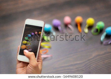 Woman makes a photograph of the colorful easter eggs with her cell phone. Mobile photo. Copyspace and place for text and wording. Easter concept