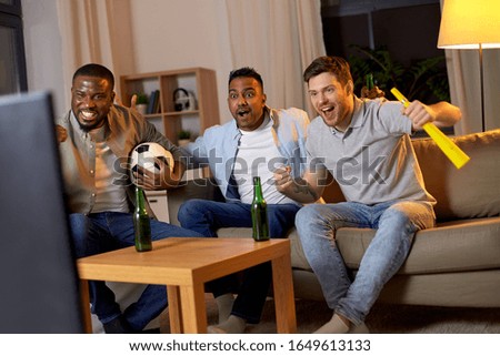 friendship, sports and entertainment concept - happy male friends with soccer ball and vuvuzela supporting football team at home