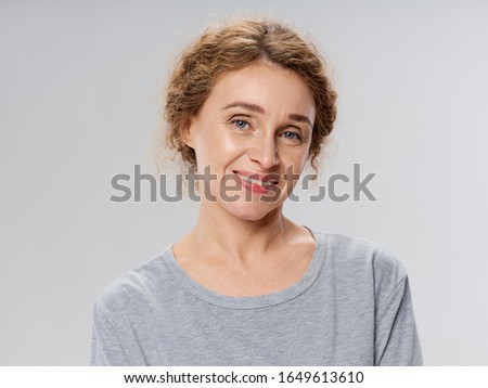 Beautiful elderly woman smiling at the camera wearing a gray tank top