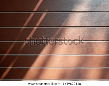 The shadow that lay over the wooden wall of the house makes it feel relaxing.