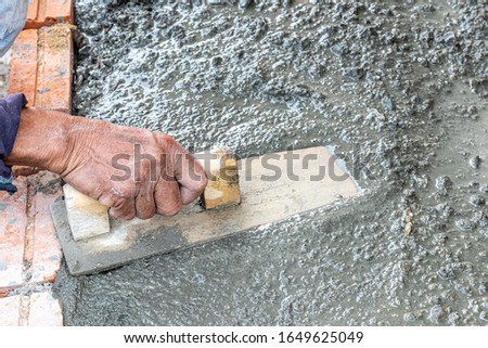 Professional worker using trowel for building cement floor.