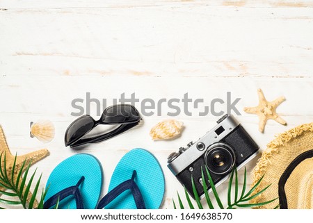 Summer travel background. Old film camera, hat, flip flops, shell and palm leaves on white background.