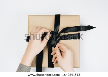 Partial view of woman tying ribbon on gift box isolated on white