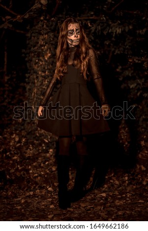 Halloween, a young girl dressed as a Mexican skull in black dress, sepia edition she looking at camera scared