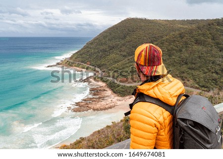 Hiker man with Beautiful beach scene, on Great Ocean Road, Melbourne, Australia. View of rock cliff edge, with ocean waves through bay. Beach, tourist, hiking, sand, sea, holiday, vacation concepts. 
