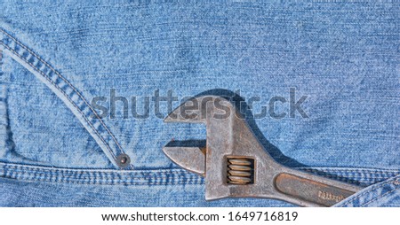 old rusty adjustable wrench in jeans pocket, labor day concept