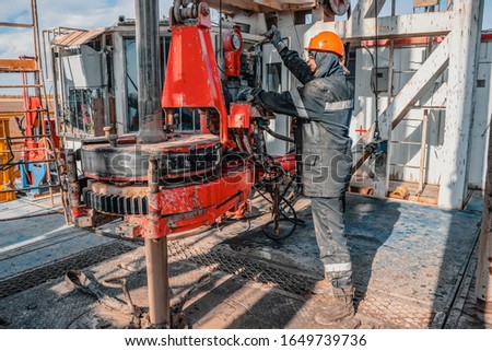 Offshore oil rig worker prepare tool and equipment for perforation oil and gas well at wellhead platform. Making up a drill pipe connection. A view for drill pipe connection from between the stands Royalty-Free Stock Photo #1649739736