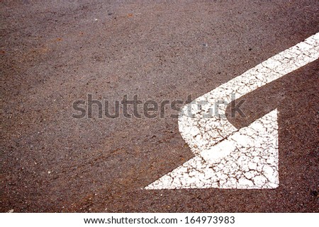 angled white painted arrow on road surface indicating left turn