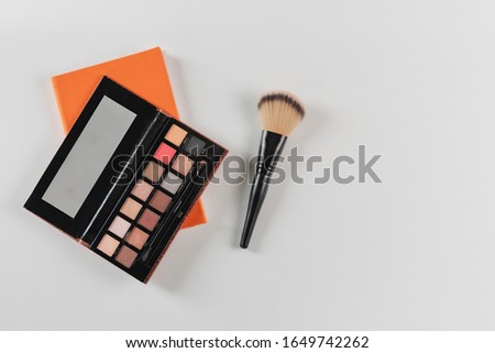 Makeup artist's notebook with palette and blush brush on white background. Copy space, top view.