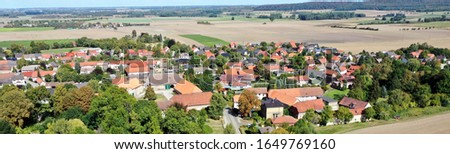Aerial panoramic close up from the center of a German village at a forest next to wheat fields