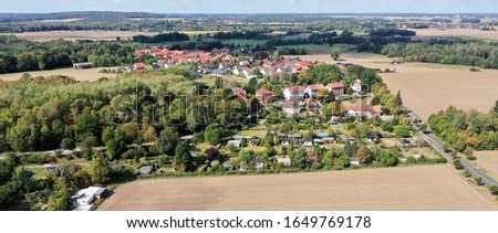 Aerial panorama of a German village at a forest next to wheat fields
